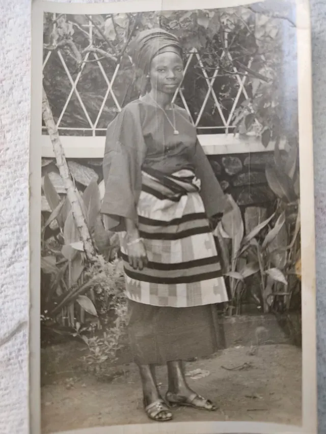 A vintage full-length photograph of a young Deaconess Victoria Badejoko Lawoyin standing outdoors in traditional attire.