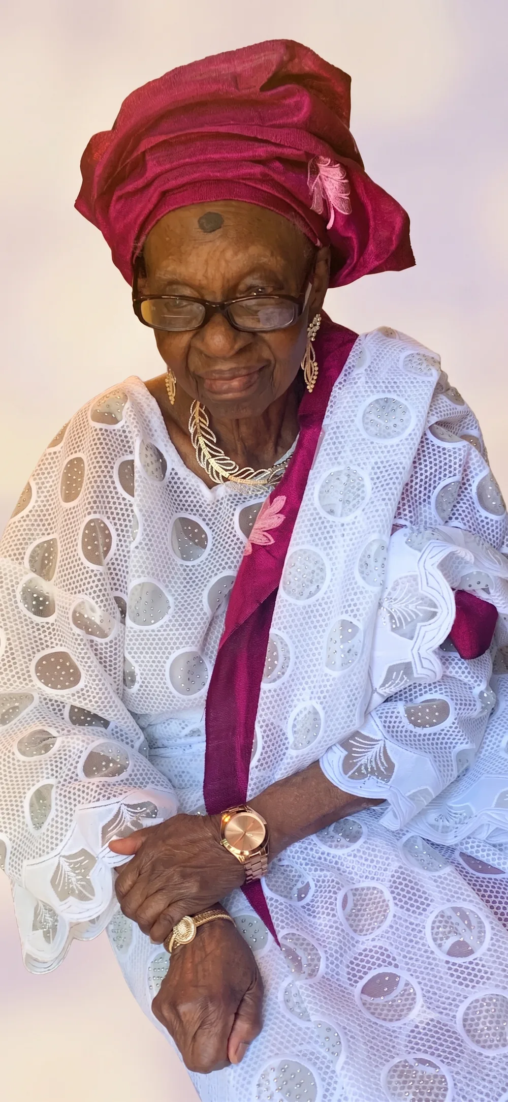 Deaconess Victoria Badejoko Lawoyin in white lace with a burgundy gele and matching sash.